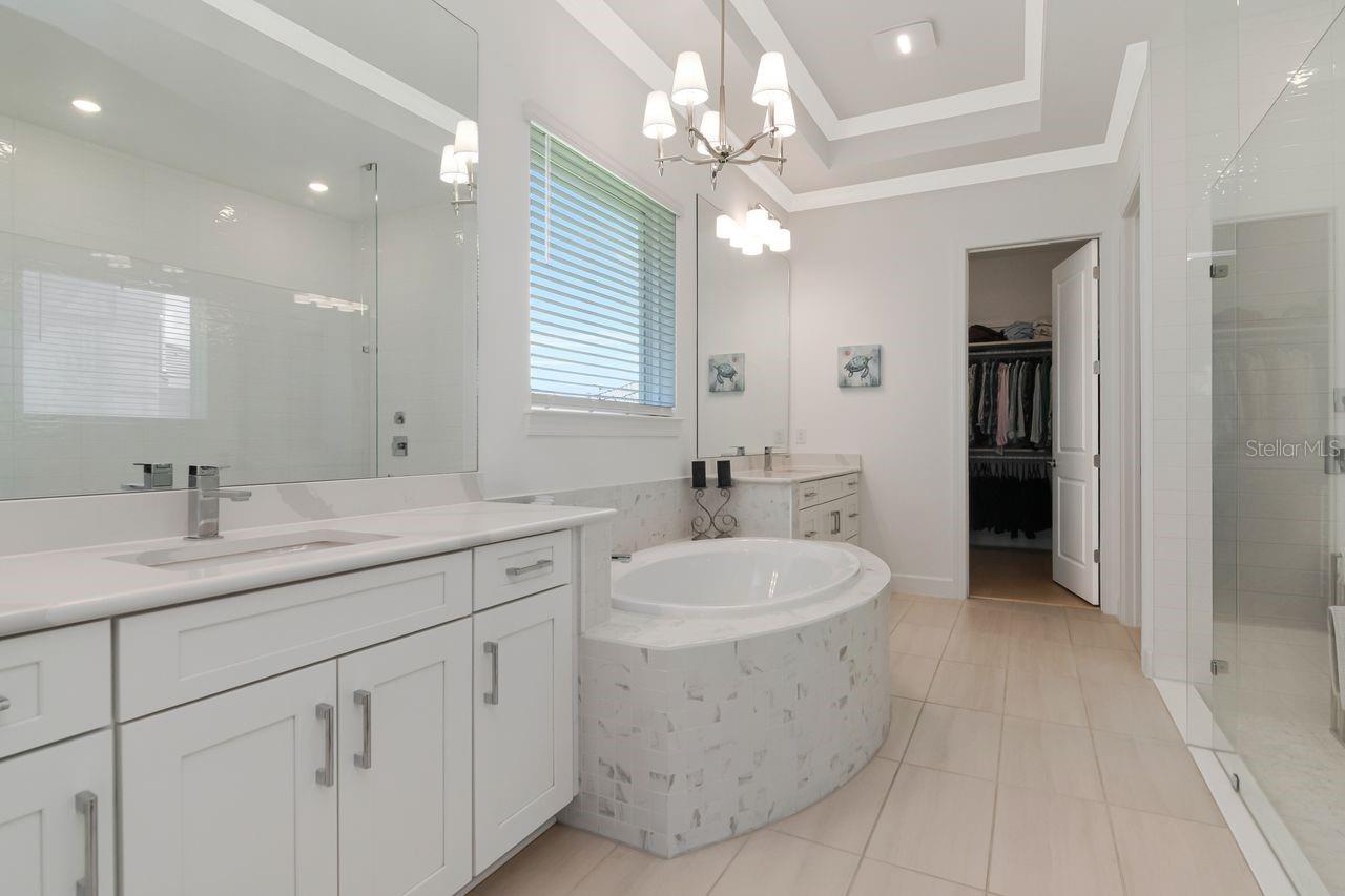 Primary En-Suite Bathroom - Tray Ceiling with Crown Molding - Quartz Countertops - Dual Separated Vanities - Glass Framed Shower - Garden Soaking Tub - Engineered Hardwood Floors - Access to Customized Walk-In Closet