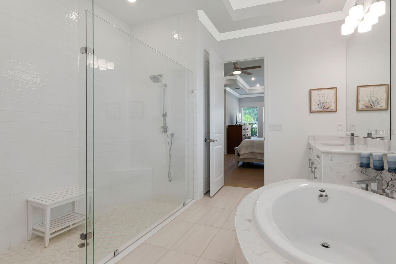 Primary En-Suite Bathroom - Tray Ceiling with Crown Molding - Quartz Countertops - Dual Separated Vanities - Glass Framed Shower - Garden Soaking Tub - Engineered Hardwood Floors - Access to Customized Walk-In Closet
