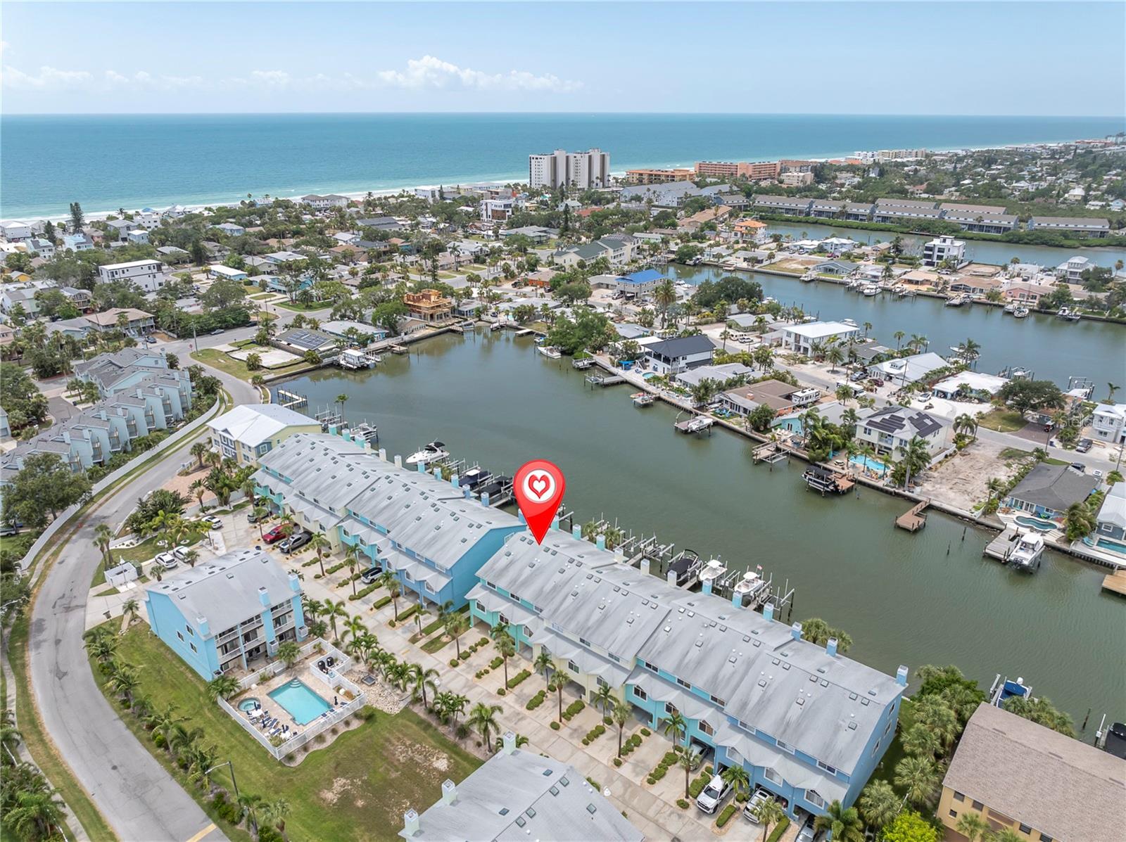 A bird's-eye look at life in Sunset Bay — a row of pastel townhomes tucked along the Intracoastal, docks lined with boats, and the Gulf shimmering in the distance. This is the view that sells the lifestyle before you even step inside.