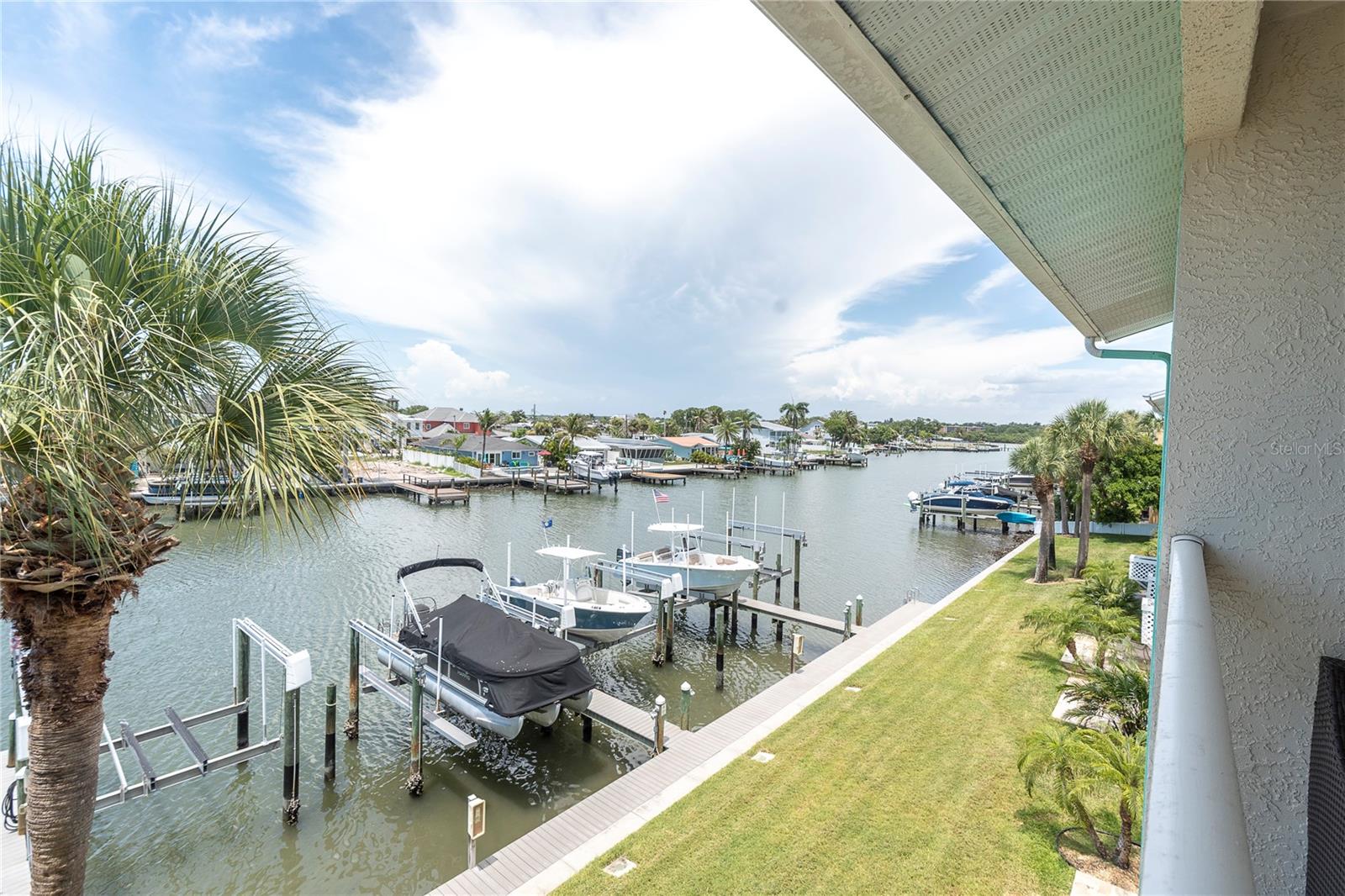 Palm fronds frame a view most people only get on vacation. From here, the dock, the lift, and the whole waterway feel like they're part of your morning routine.
