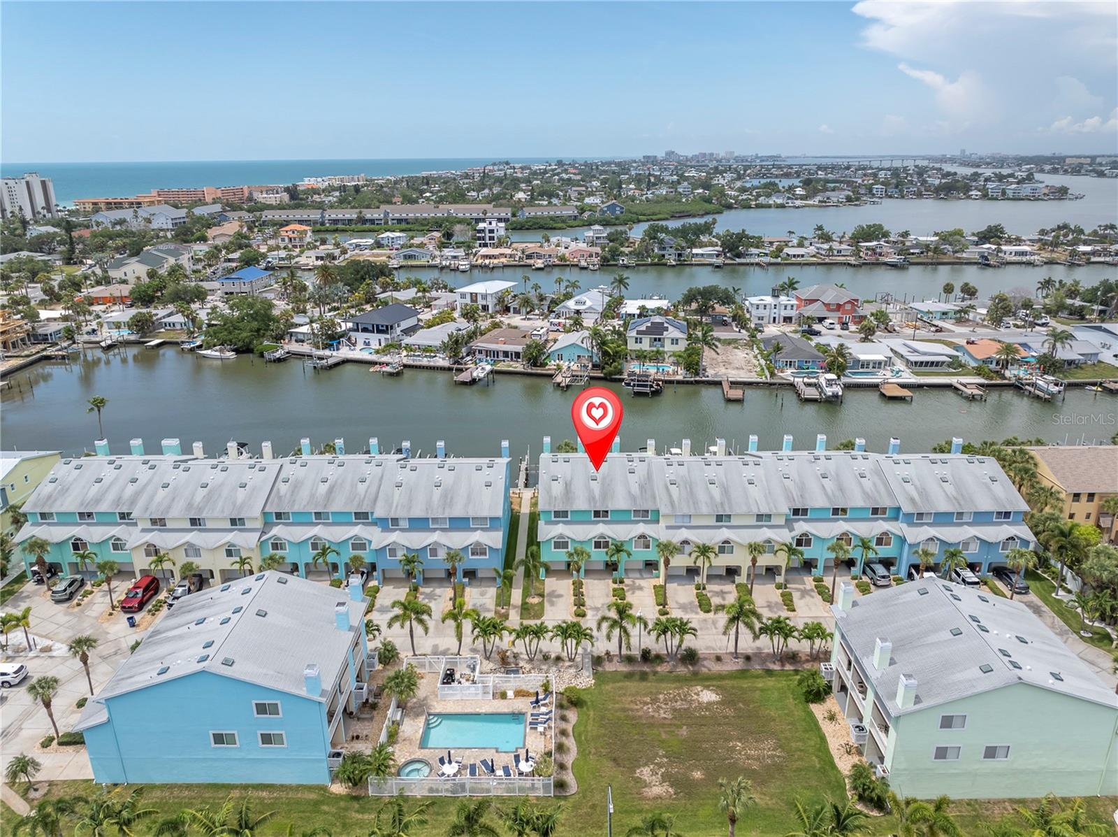 A bird's-eye look at life in Sunset Bay — a row of pastel townhomes tucked along the Intracoastal, docks lined with boats, and the Gulf shimmering in the distance. This is the view that sells the lifestyle before you even step inside.