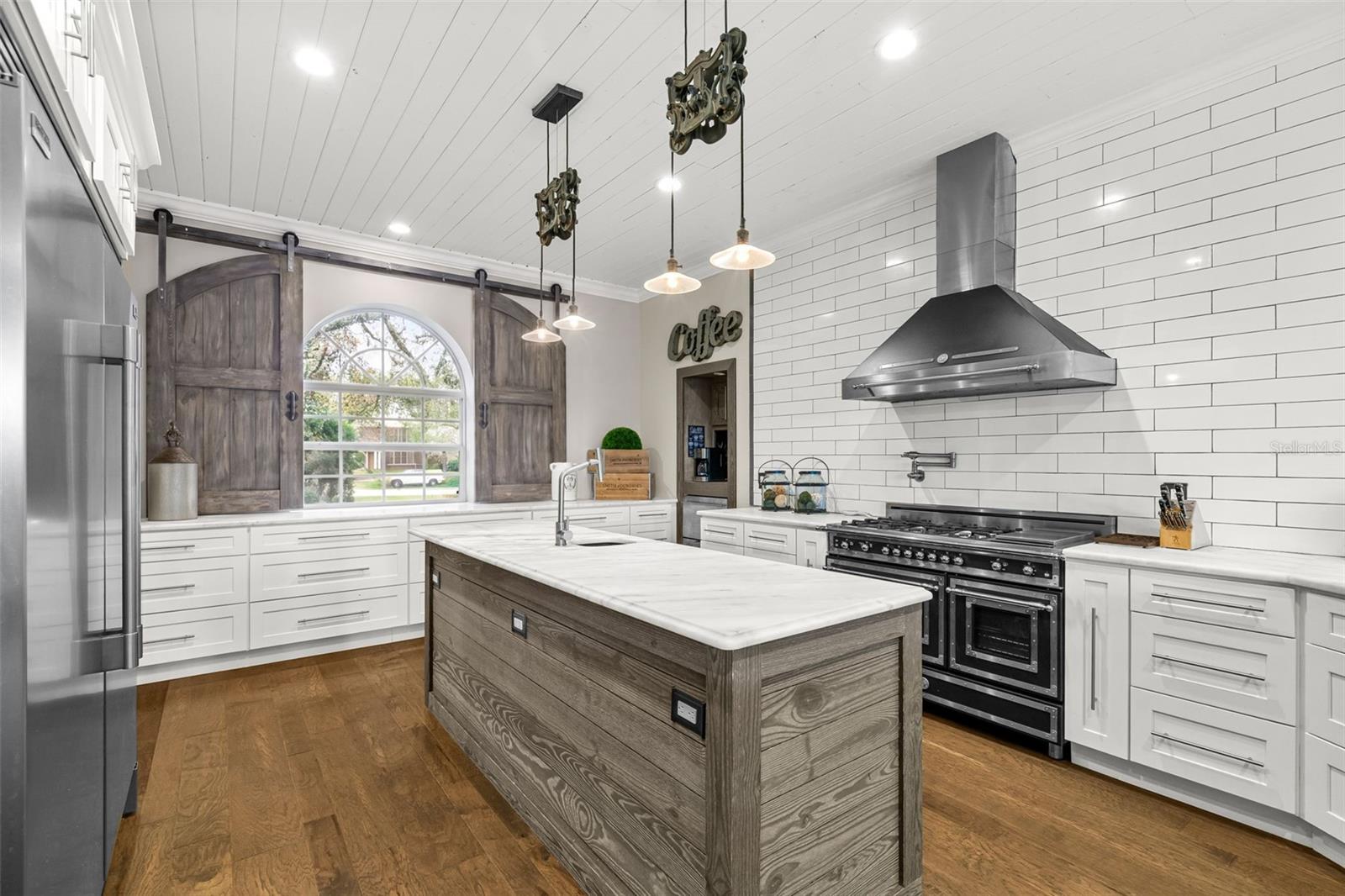 Custom finishes and carefully curated details—including the distinctive barn-door window feature—add warmth and personality throughout the kitchen.