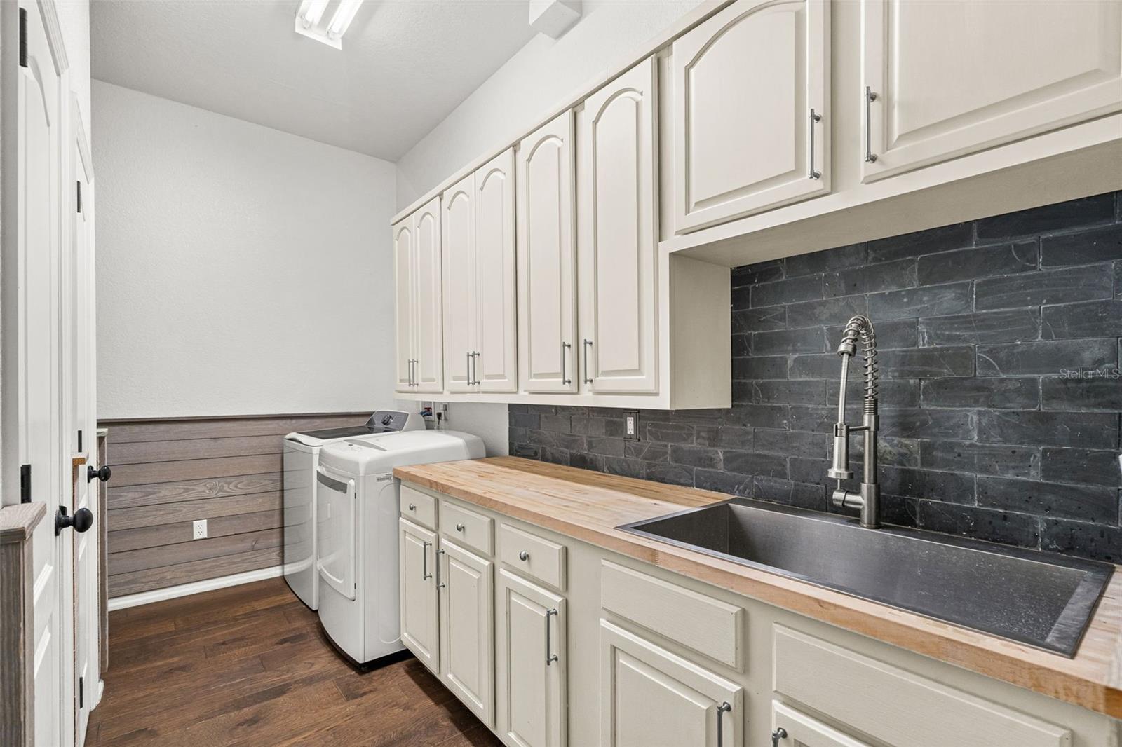 Designed with everyday convenience in mind, the spacious laundry room offers abundant cabinetry, generous countertop space, and a utility sink to simplify daily routines.