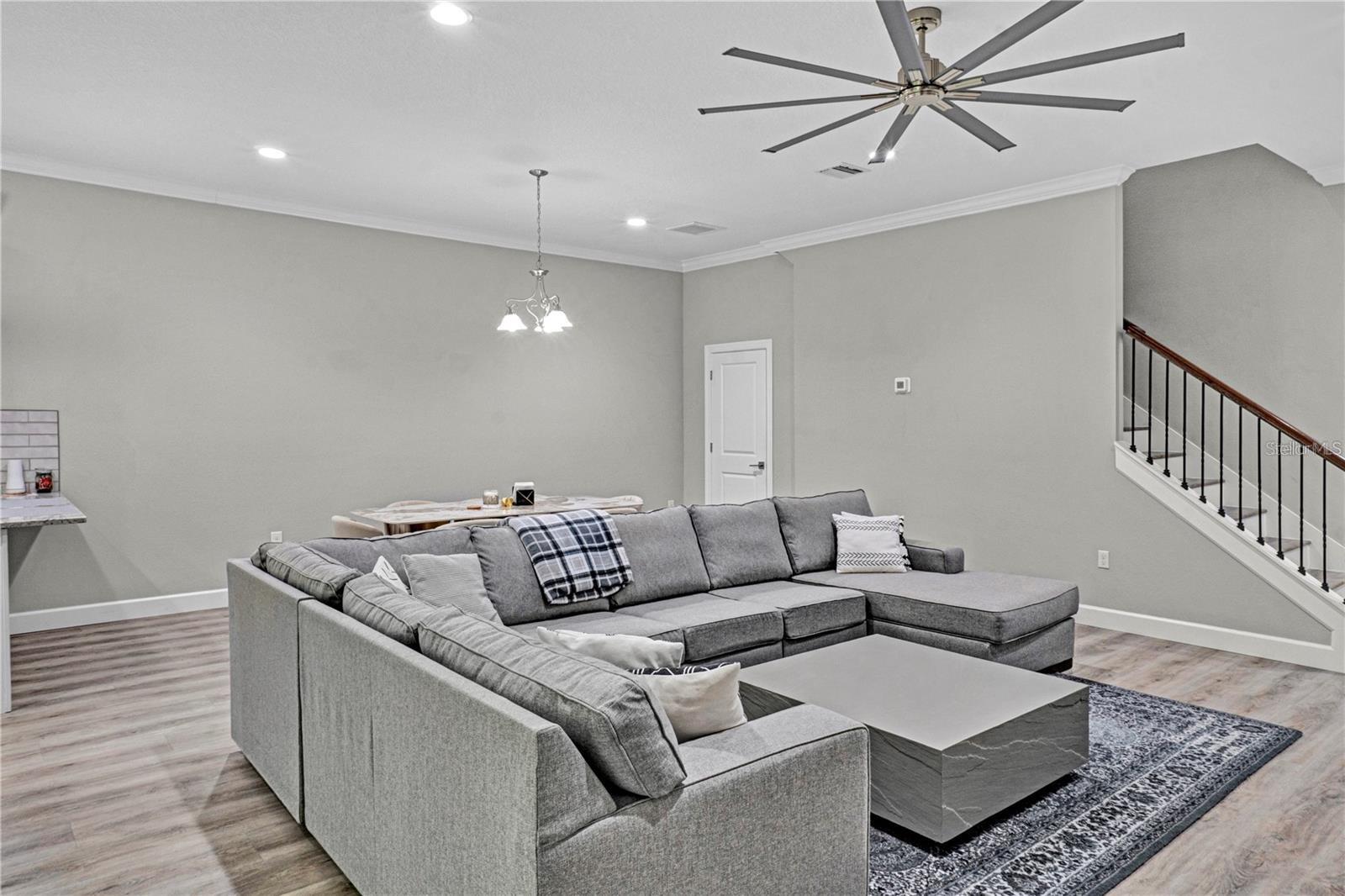 The expansive, open-concept main floor features durable wood-look flooring, modern recessed lighting, and a massive ceiling fan designed to keep the entire living space cool and comfortable.