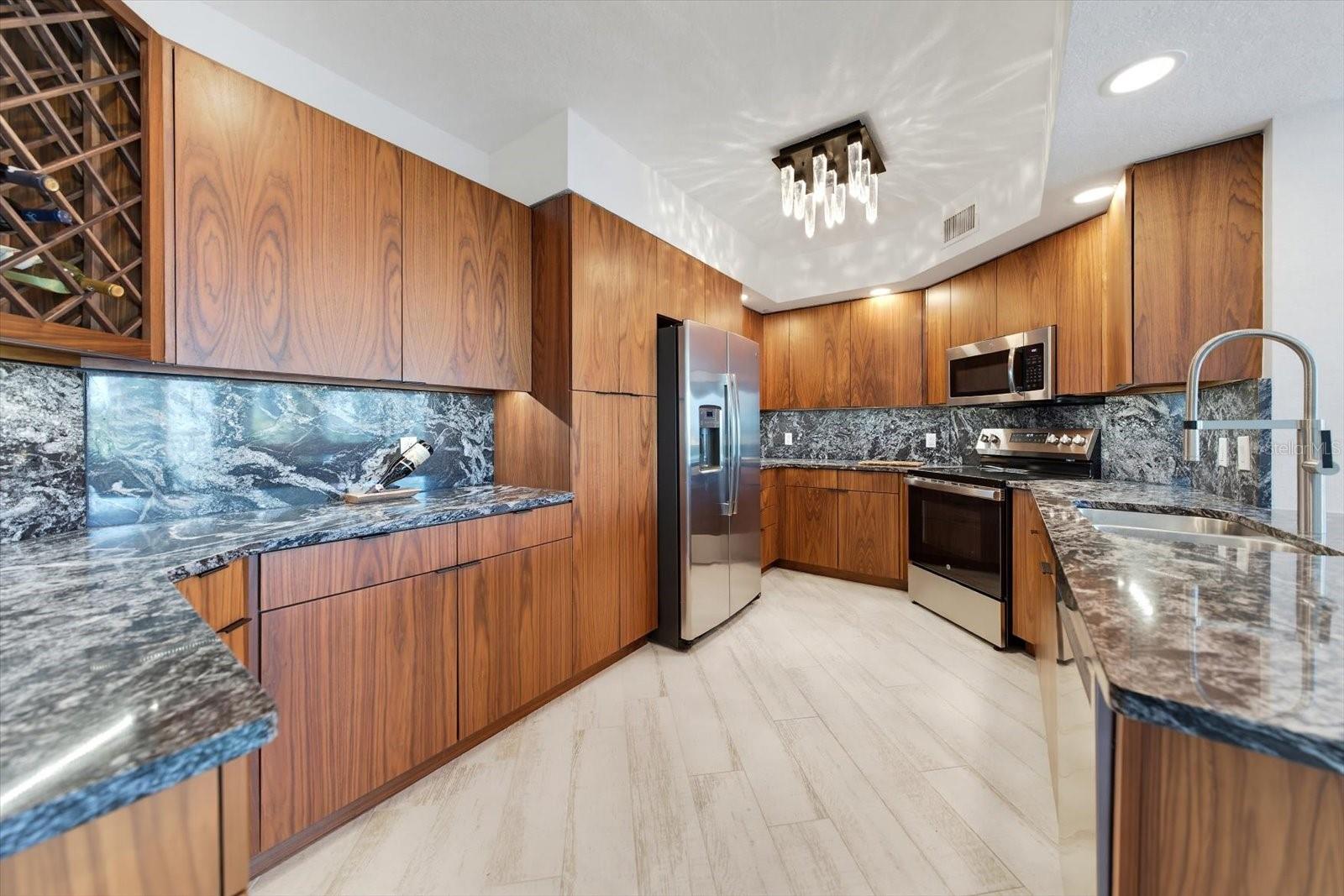 Designer kitchen featuring custom light & cabinetry offers ample & efficient storage.