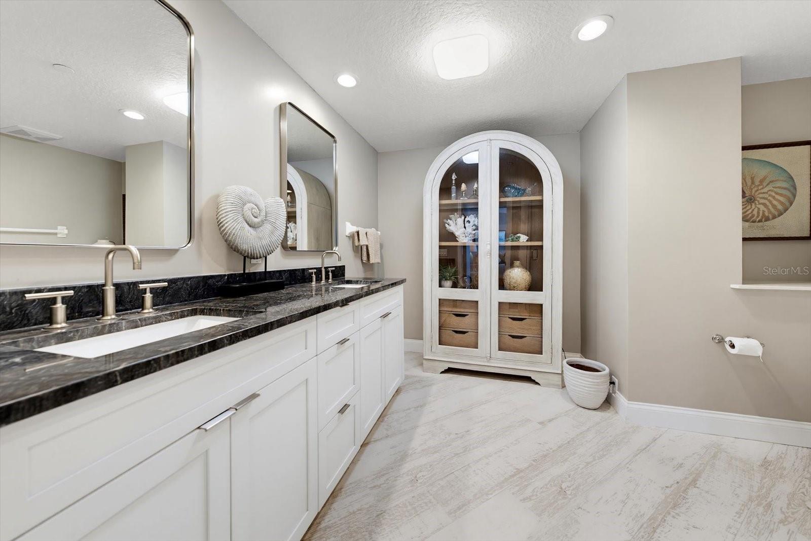 En-suite bathroom with high counter dual vanity & custom cabinet for additional storage.