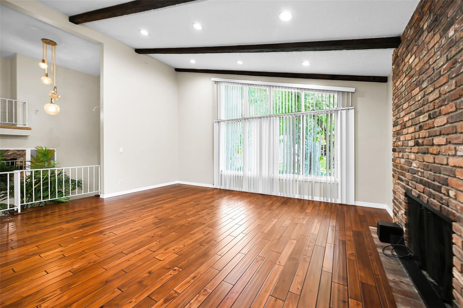An impressive living space highlighted by soaring beamed ceilings, a substantial fireplace, and beautifully finished hardwood flooring