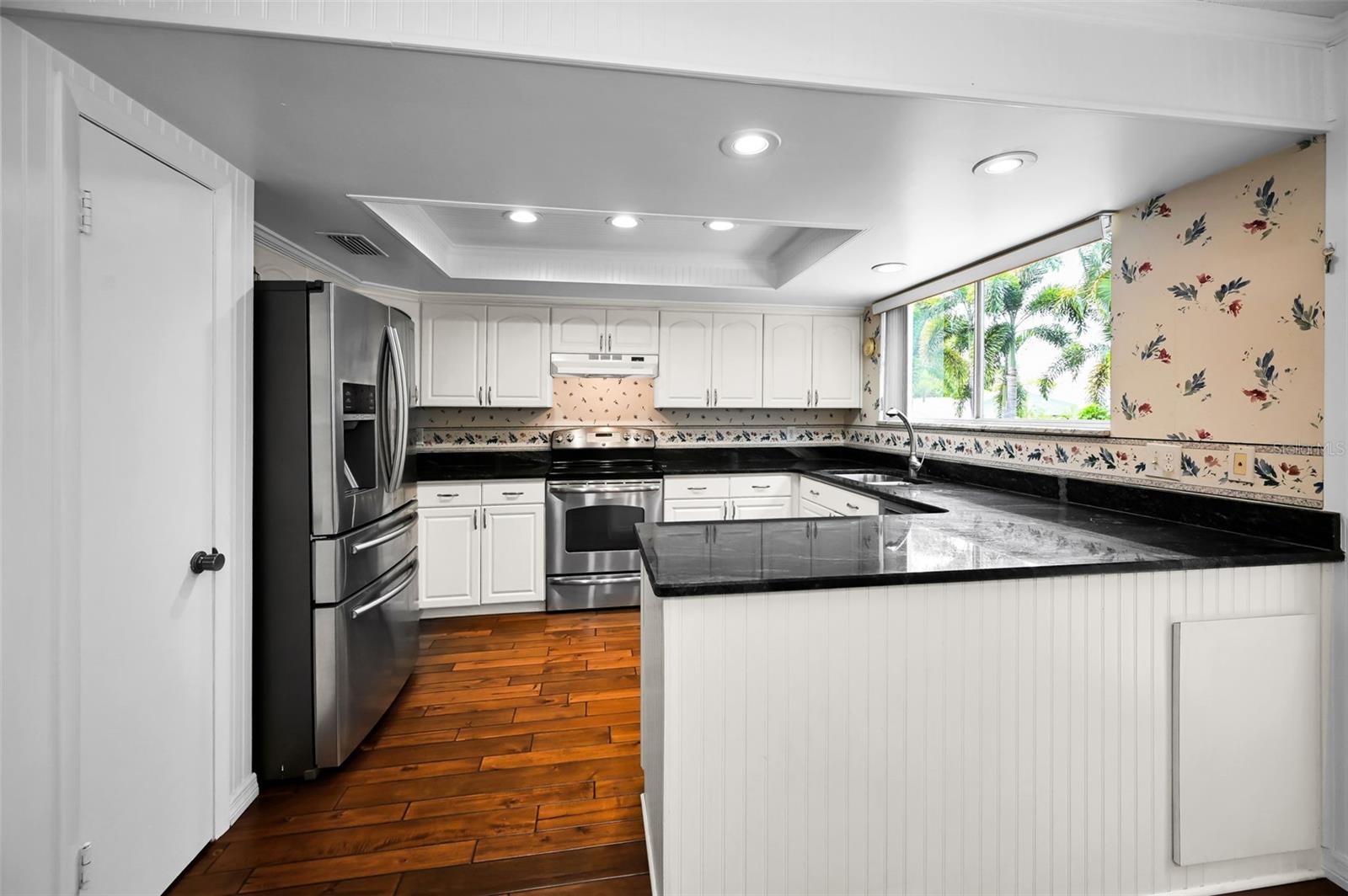A refreshed contemporary kitchen with shaker cabinets and seamless flow into the dining and family rooms and overlooking the backyard.
