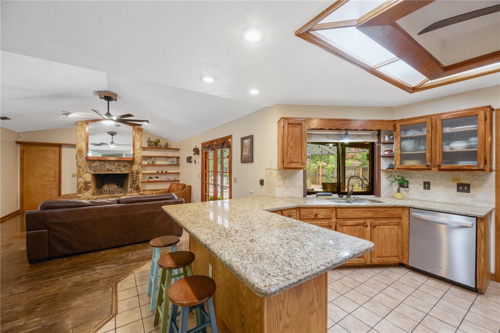 The kitchen is designed for both everyday living and entertaining with granite countertops, abundant cabinet and counter space, a double pantry for storage, and a convenient pass-through window above the sink overlooking the pool and lanai.