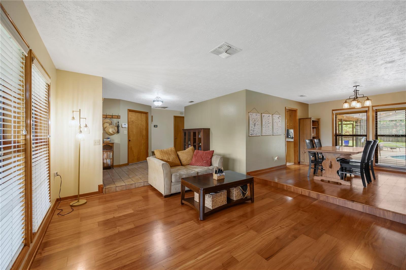 The living room / dining room feature wood floors and views of the front porch and back lanai.