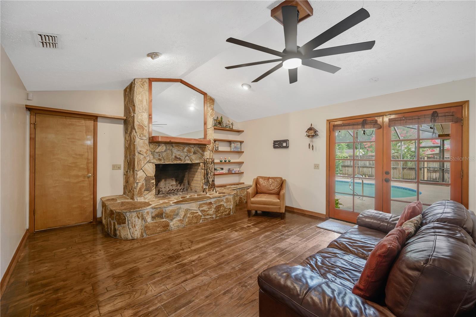 The spacious family room features a cozy fireplace and French doors that open to the screened lanai.
