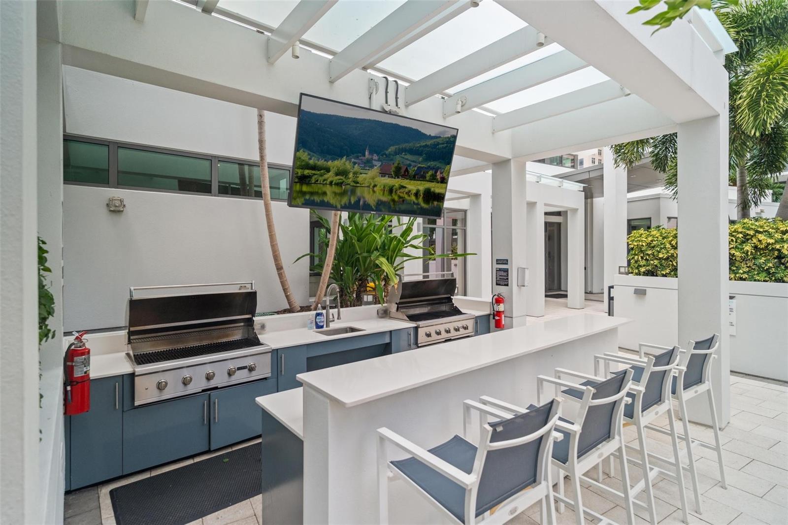 Multiple BBQ grill areas with built-in fridge and outdoor TV for sports viewing