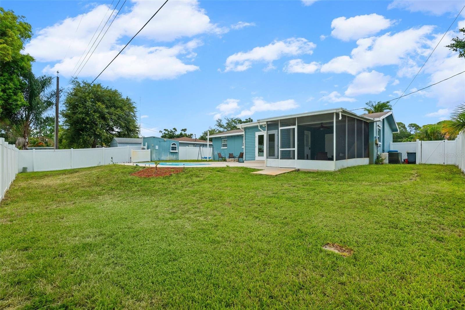 large fenced in backyard with pool, shed and fire pit.