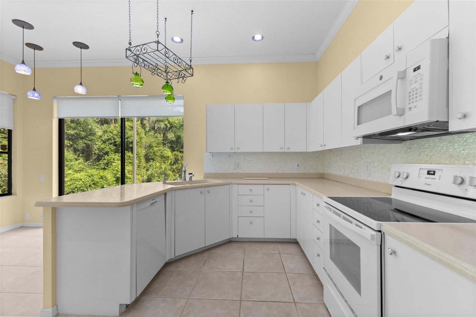 Well-maintained kitchen with generous cabinet space, breakfast bar, and an eat-in dining area overlooking the private backyard.
