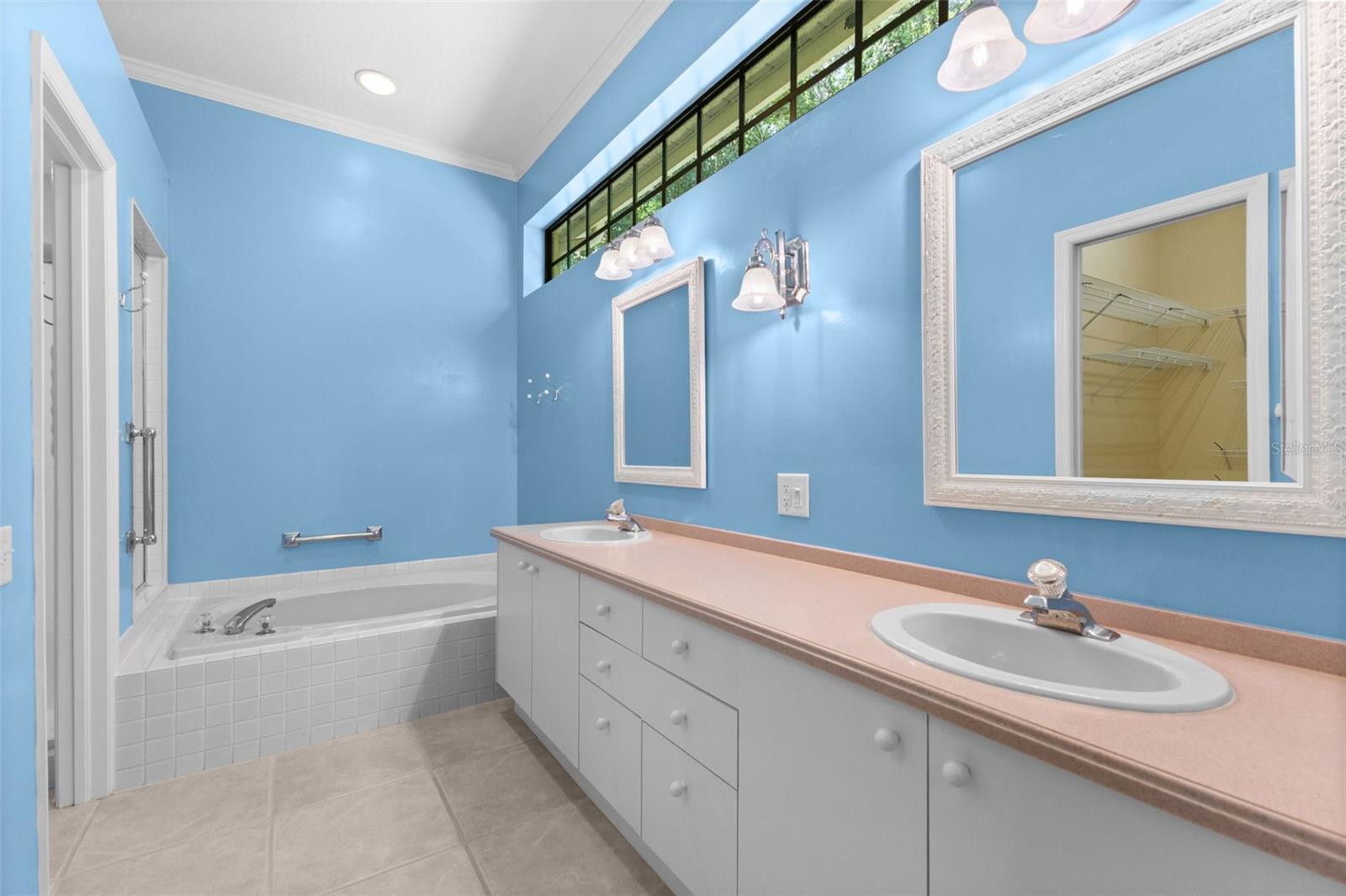 Primary bath features dual vanities, soaking tub, separate shower, and generous storage.