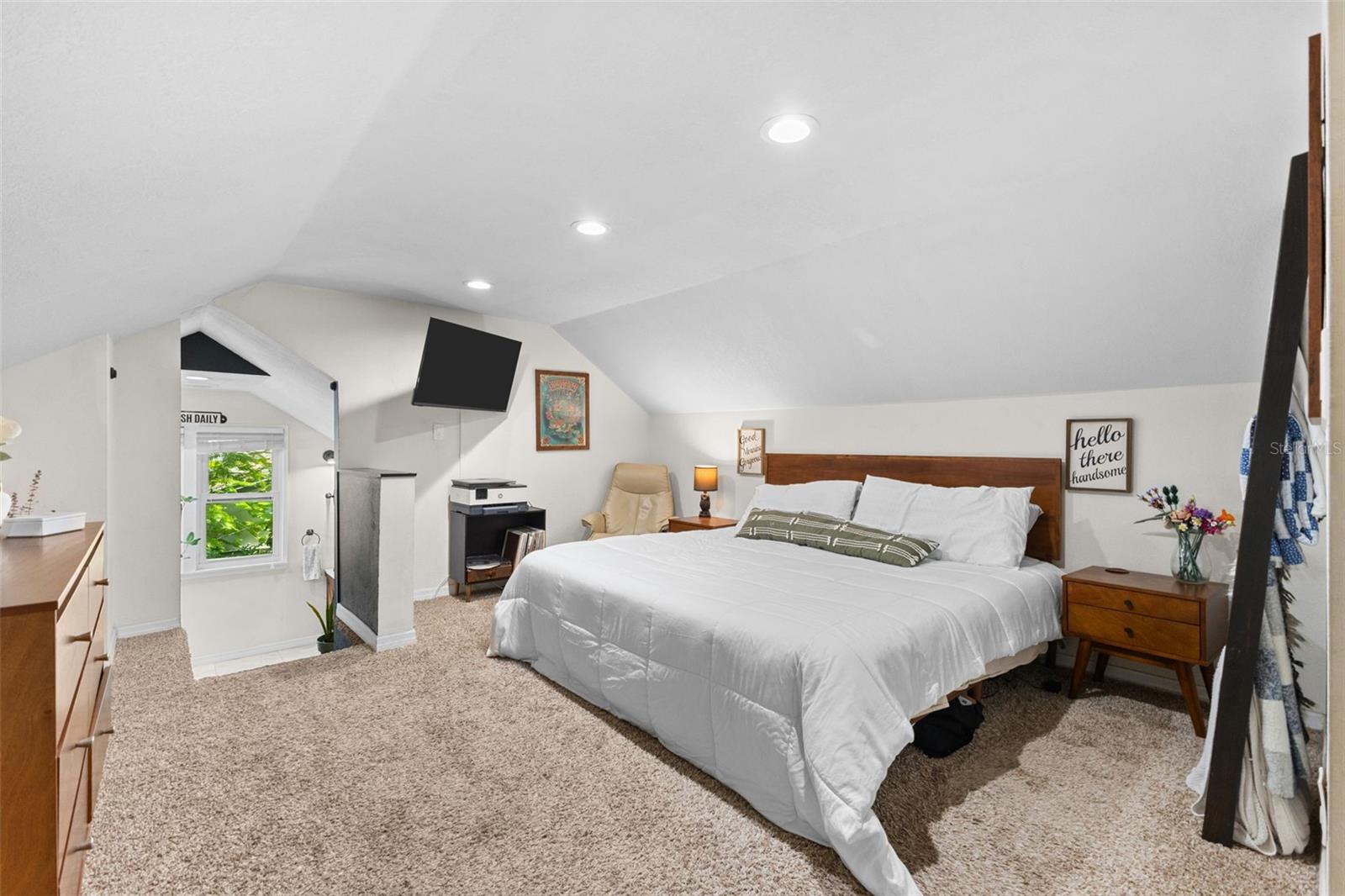 The primary suite runs the full upper level — cozy window-seat nook and en-suite bath tucked under charming angled ceilings.