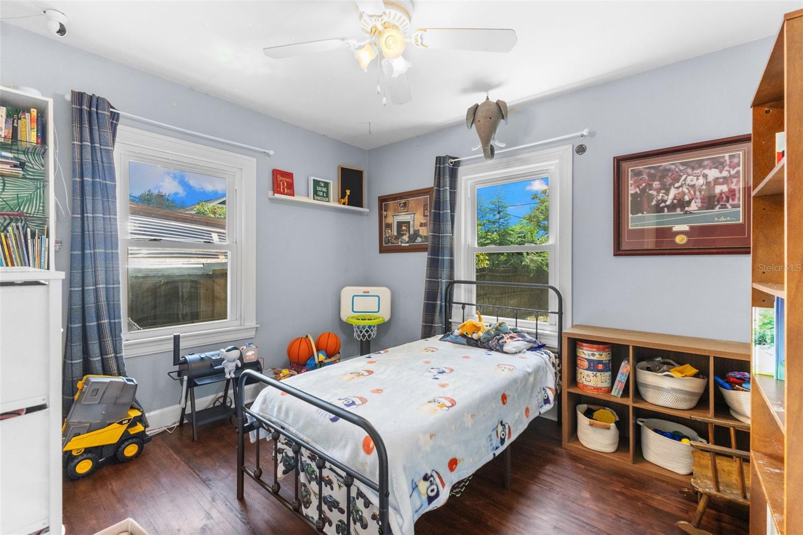 Comfortable main-floor bedroom with original hardwood floors, ceiling fan, and abundant natural light.