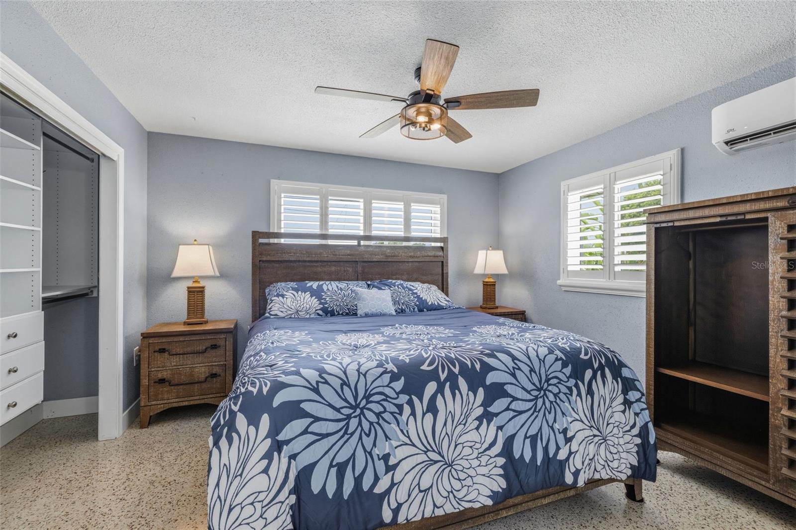 Primary Bedroom with polished Terrazzo flooring, custom ceiling fan, mini-split HVAC system, plantation shutters and custom closet organizer.