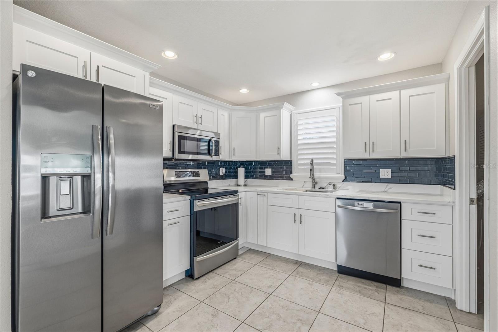 Well appointed kitchen features Quartz countertops, new stainless-steel appliance package (refrigerator, dishwasher, range & microwave), deep basin sink, with soft close drawers, cabinets and recessed lighting.