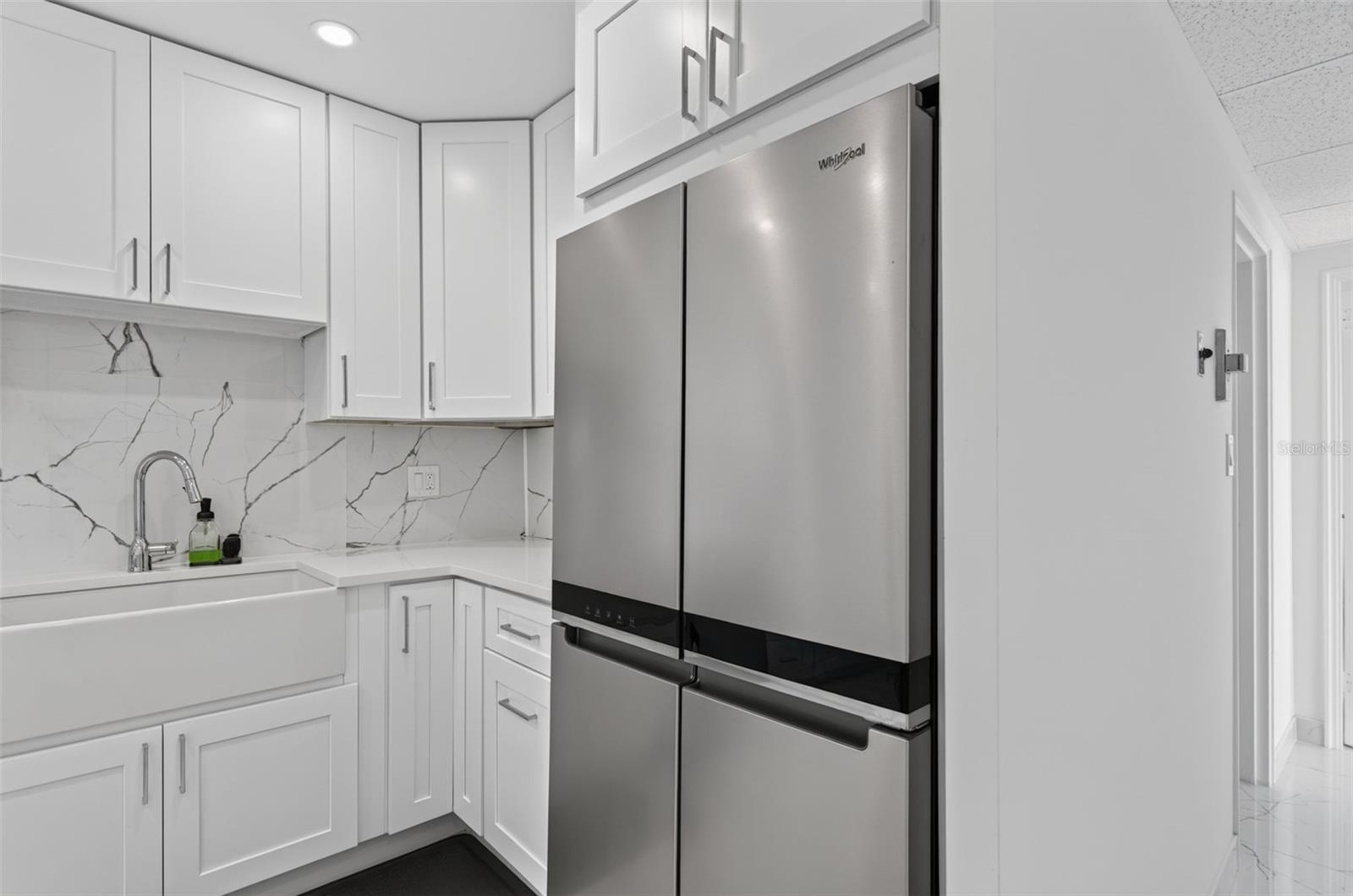 Large Refrigerator freezer and farmhouse sink add  beauty to this kitchen