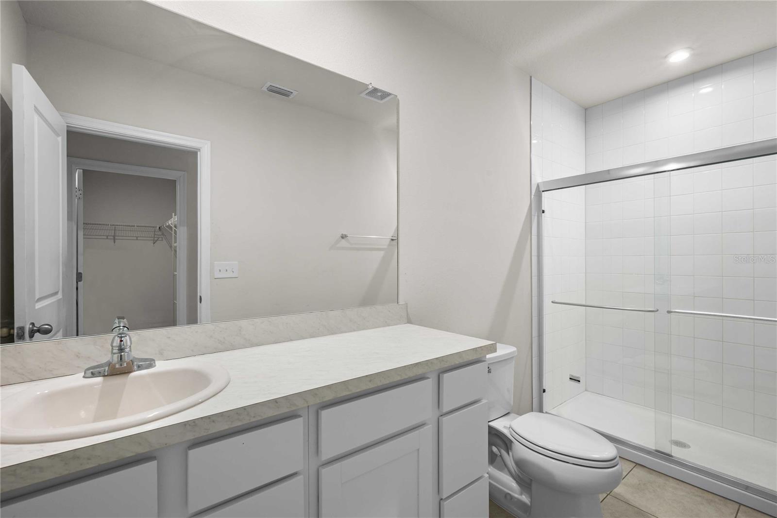 The primary bath with tiled floors and shower surround has new glass doors