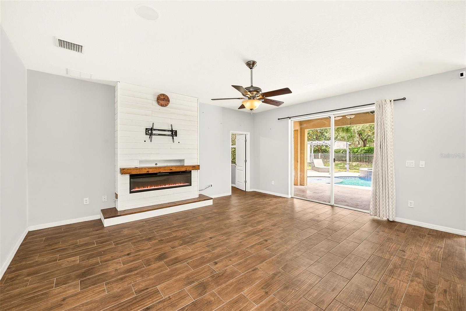 This spacious great room / family area features a modern electric fireplace and a scenic view of the backyard.