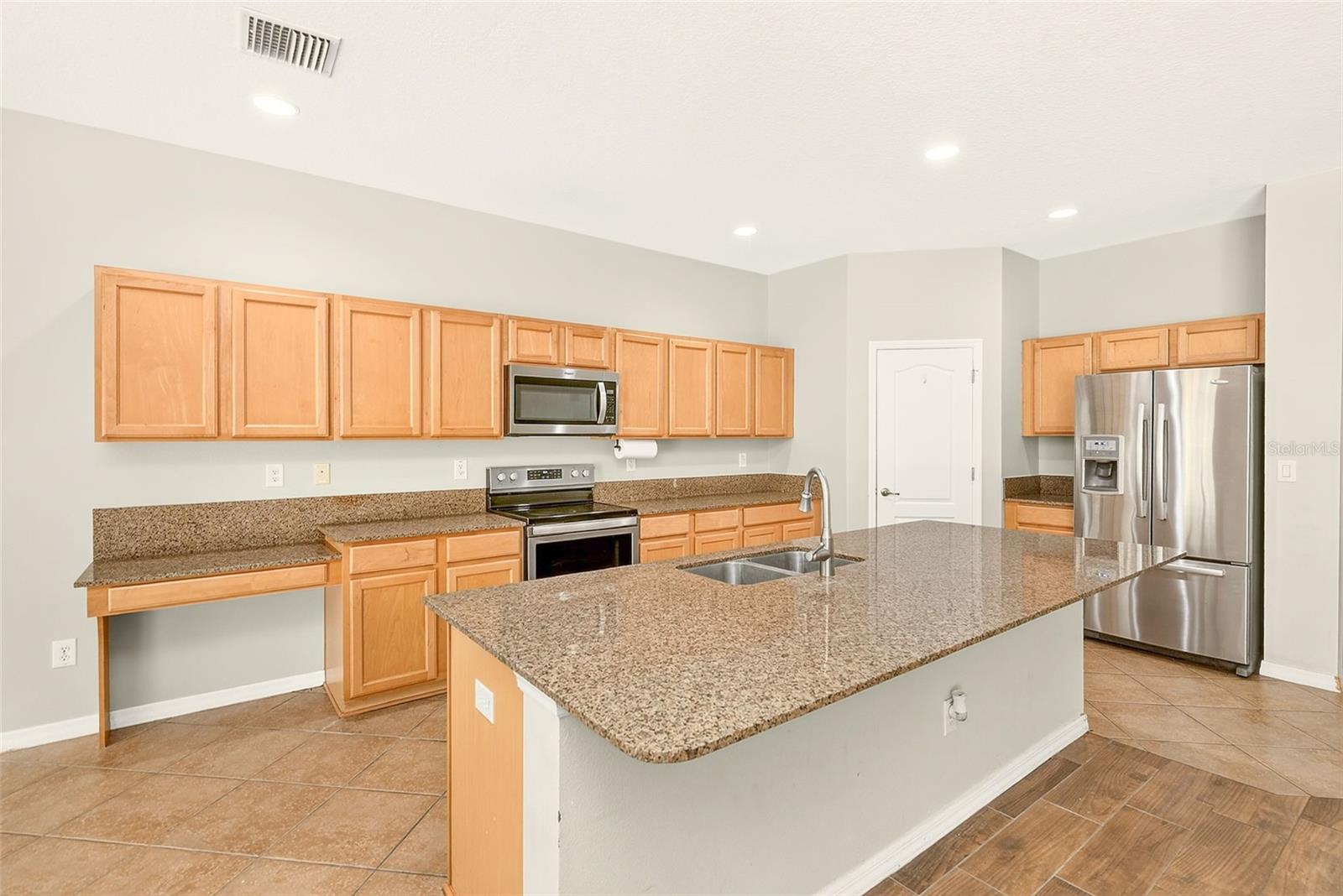 Spacious kitchen featuring stainless steel appliances, large island, granite countertops