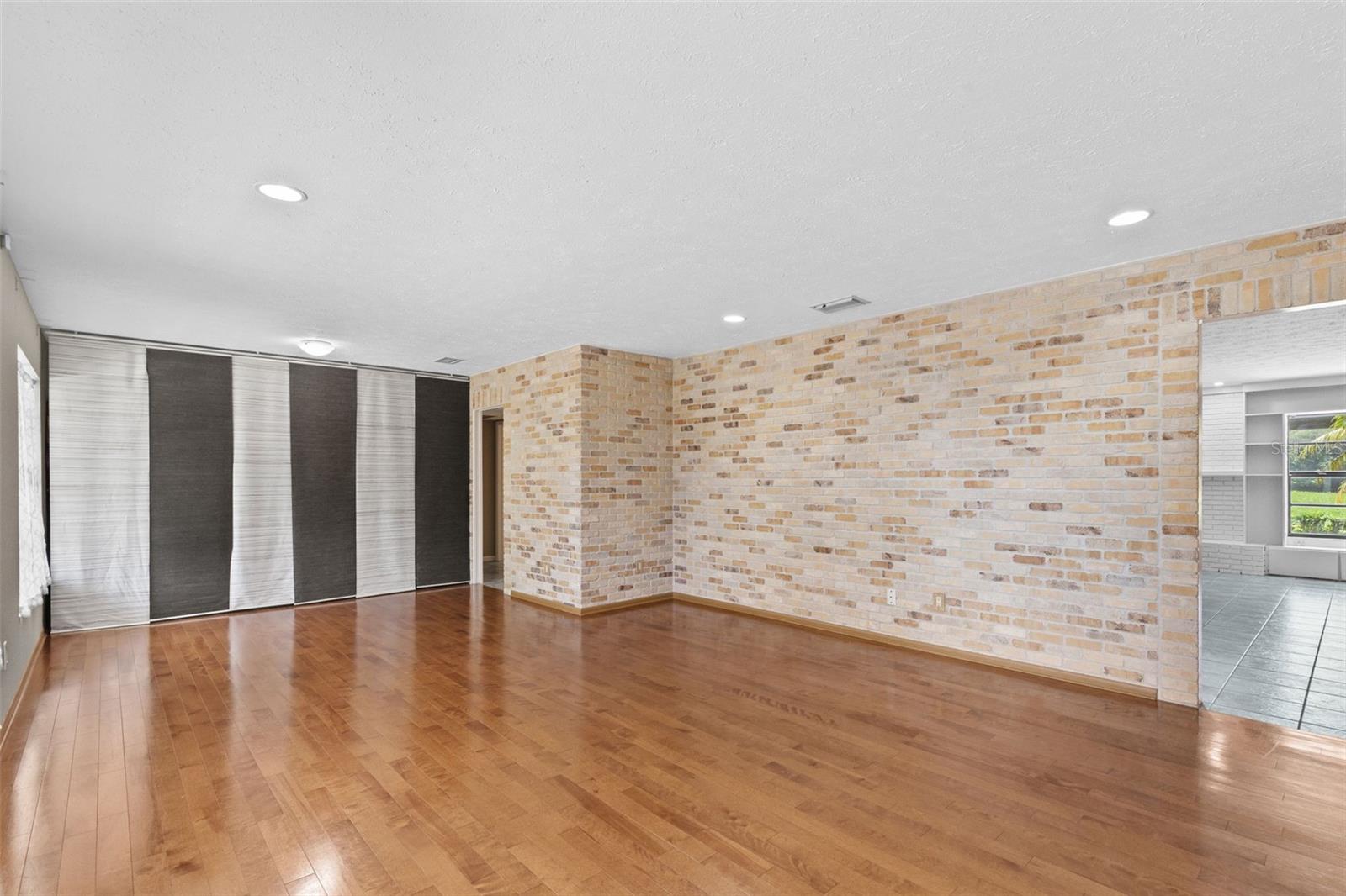 Living room/dining room has wood floors and brick accent wall