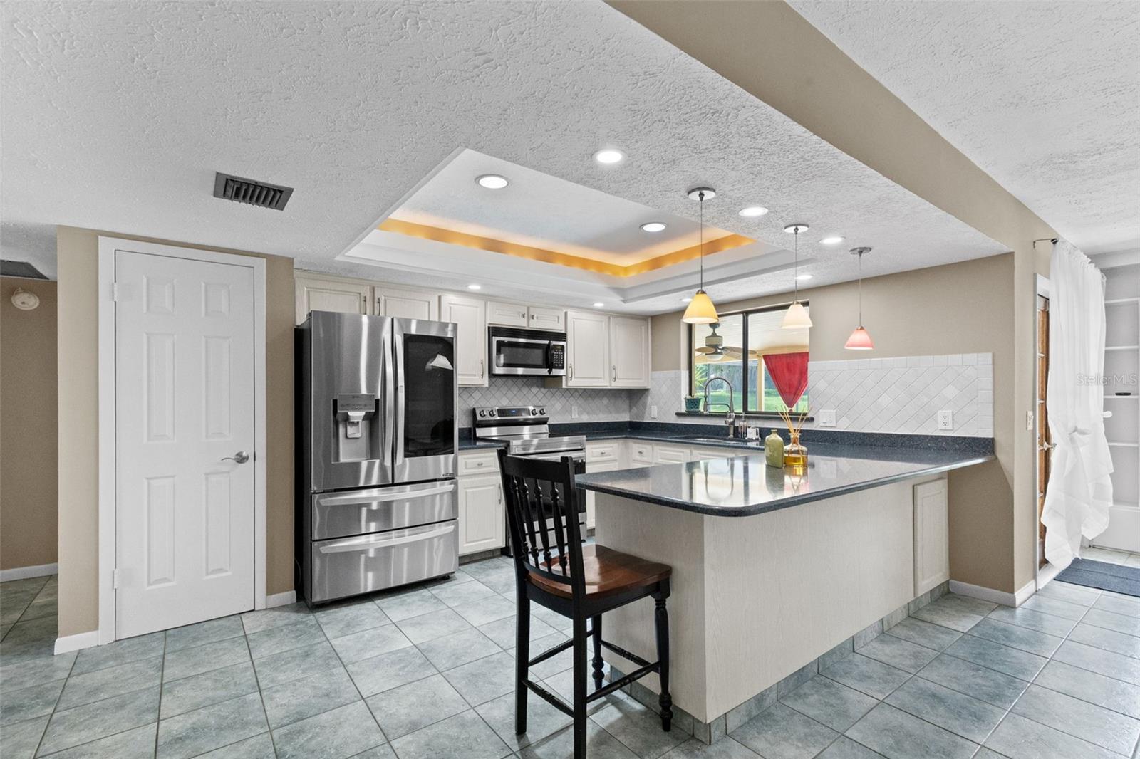 Kitchen and breakfast bar with pantry door visible beside the refrigerator.