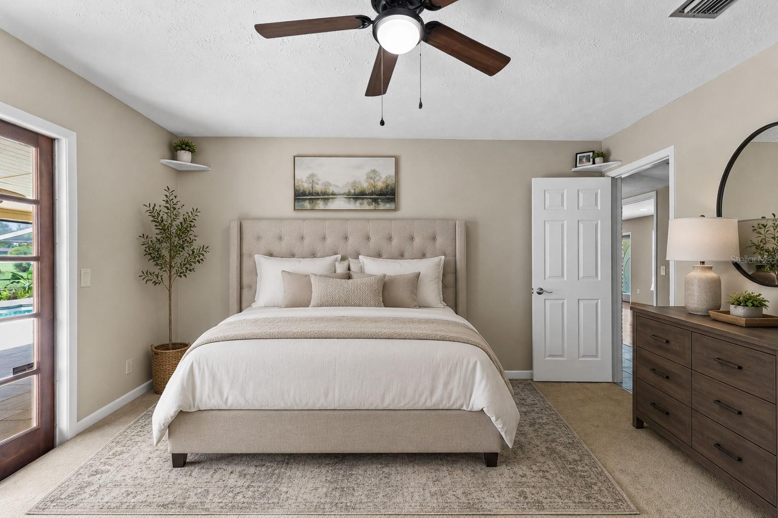 Staged premium bedroom with access to pool and lanai.