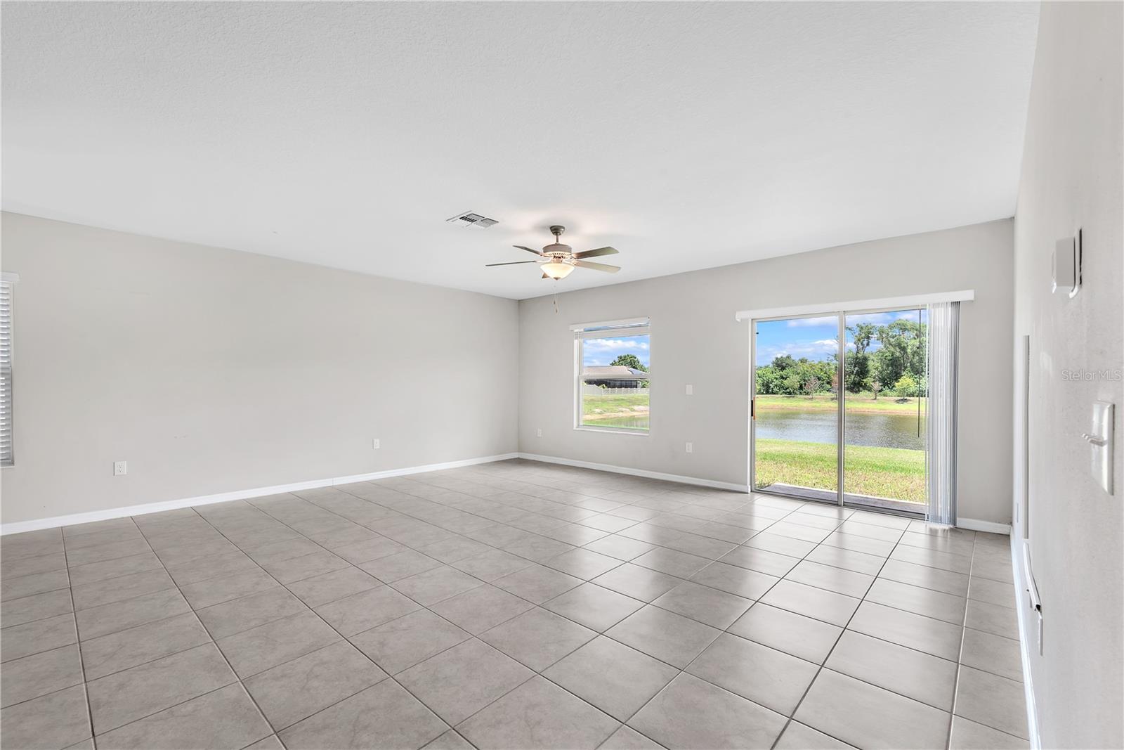 Large living room with seamless connection to kitchen and dining area over looks a pond in back.