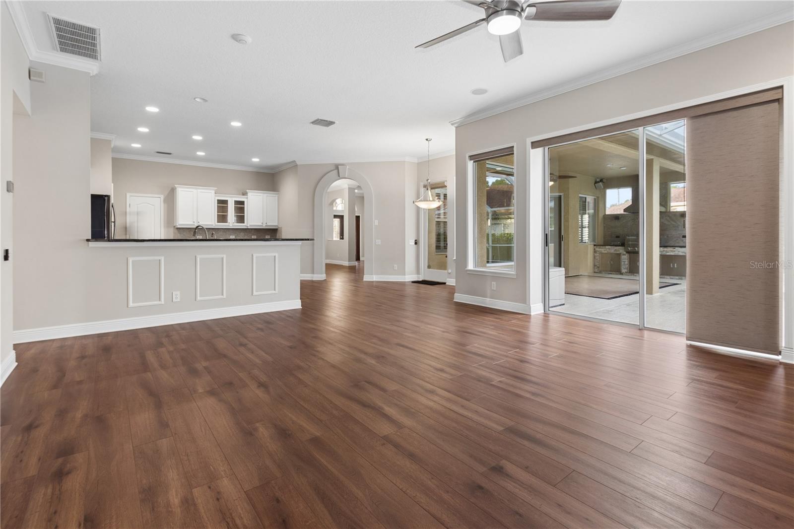 The inviting main living room features sliding glass doors that open to the screened lanai and pool, while elegant French doors lead to a versatile flex room perfect for a home office, gym, or playroom.