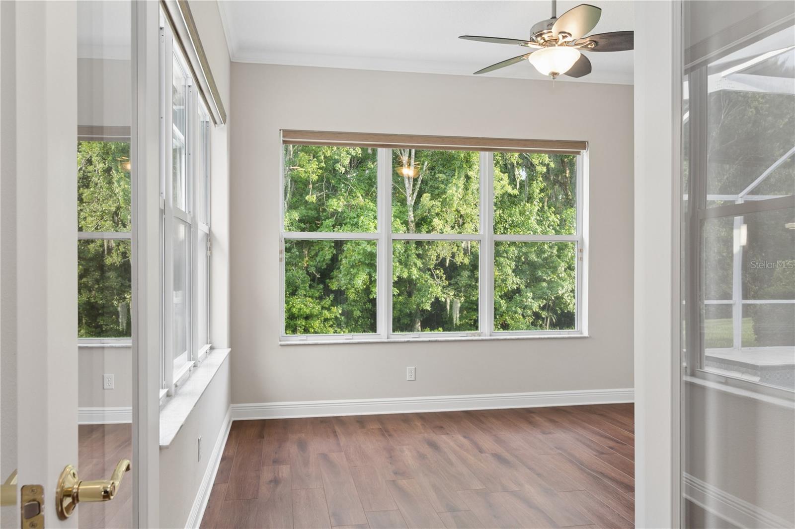 French doors open to a bright, window-lined flex room, perfect for a home office, gym, or peaceful retreat.