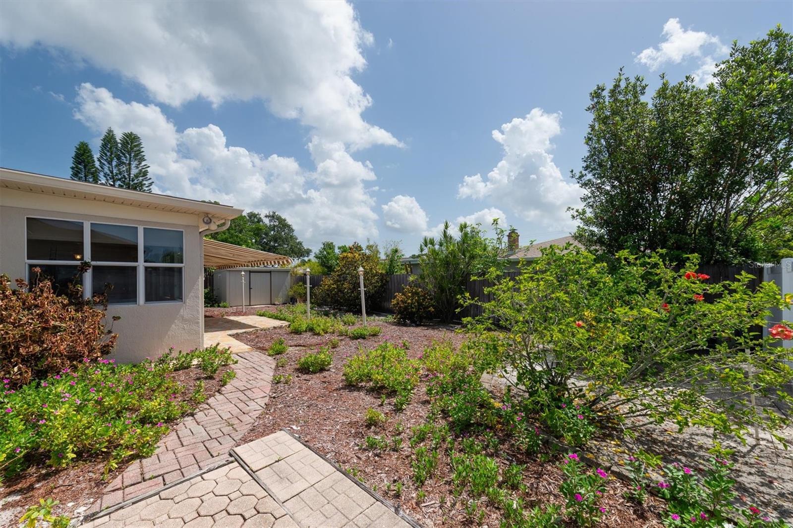 Back Patio with remote controlled Sun Shade Awnings, paver walkways, and storage shed with electricity