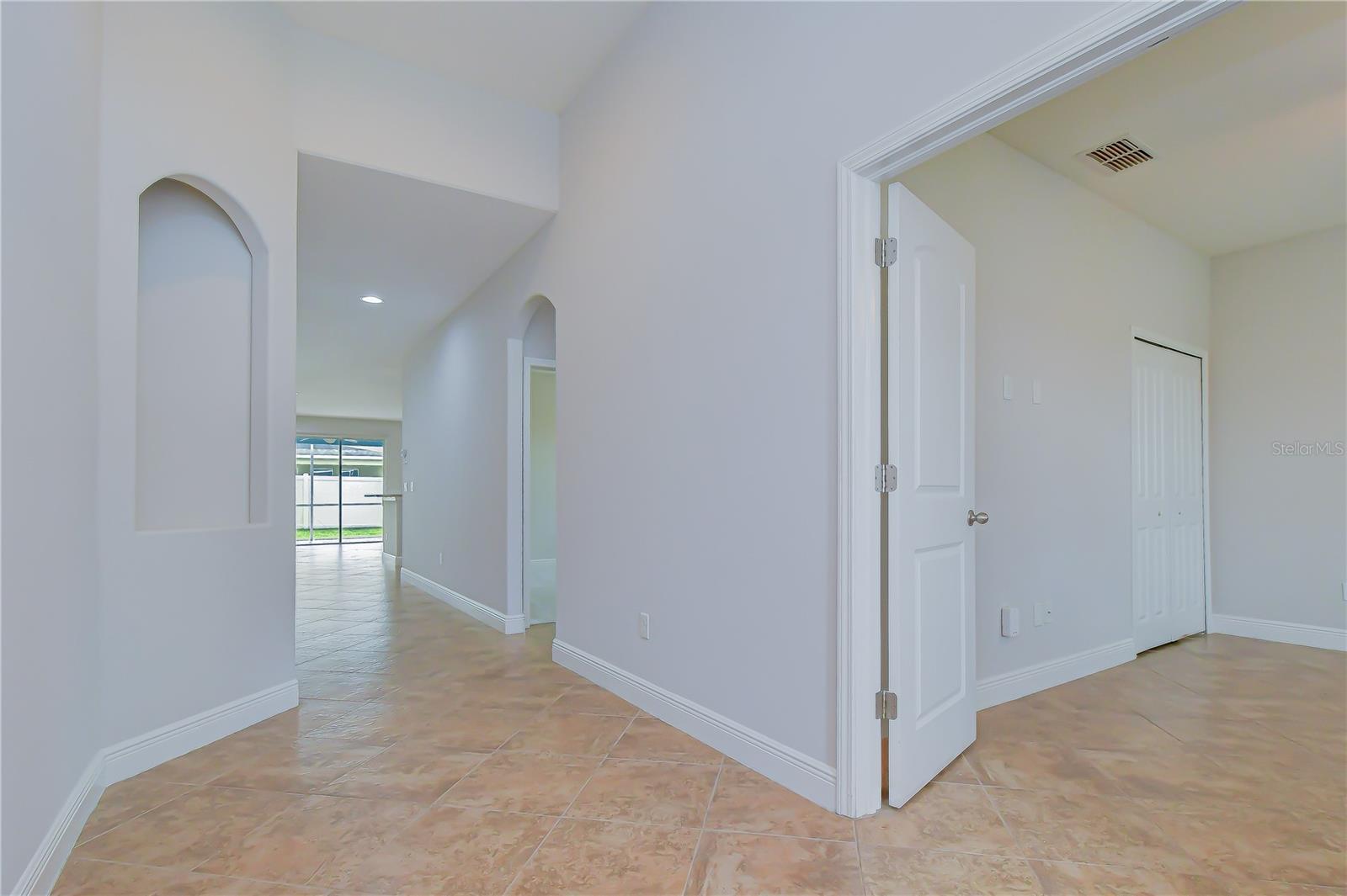 Bright hallway foyer offering seamless transitions into a private office behind double French doors and the main living areas.