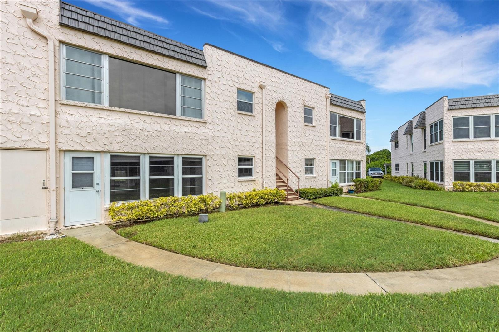 Rear of Unit with Pedestrian Door and Walkway to Pool and Clubhouse