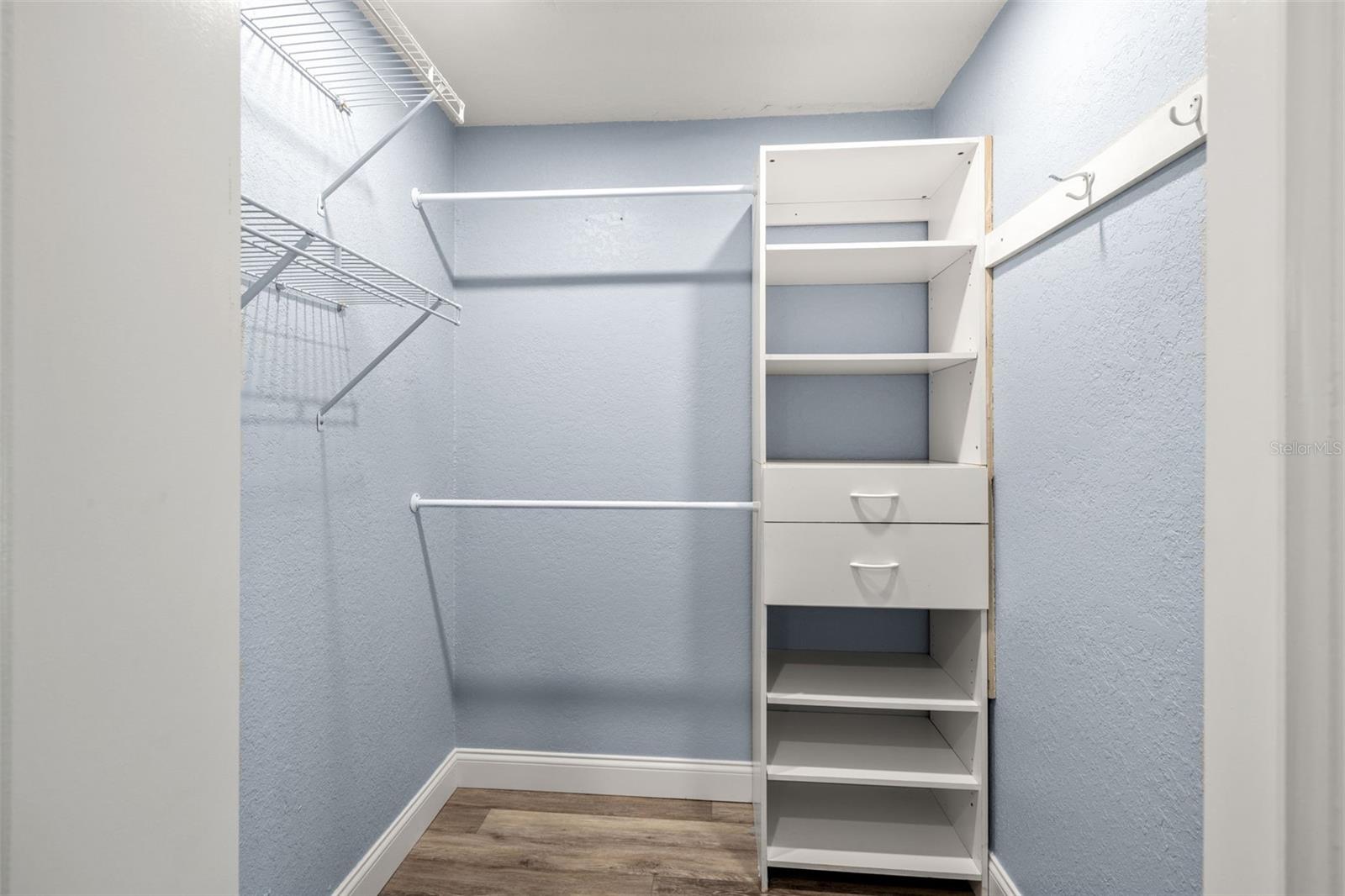 Custom shelving lines this walk-in closet, offering organized hanging and storage space just steps from the primary bath.