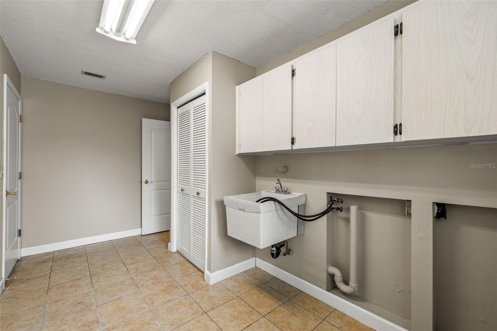 Full-height cabinetry offers generous storage in the laundry room, keeping detergents and household supplies neatly out of sight in a dedicated utility space.