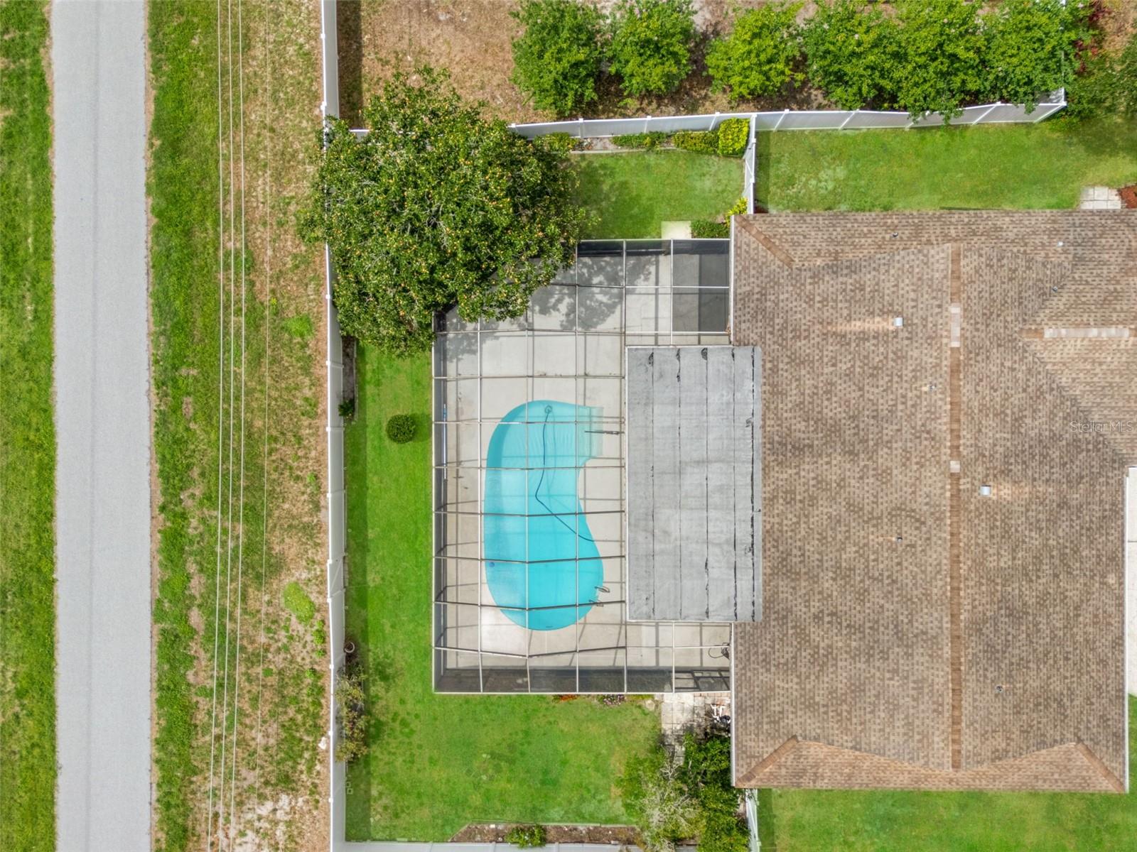 A straight-down perspective highlights the shape and scale of the pool and lanai against the home's rooftop, showcasing just how much outdoor living space this property offers.