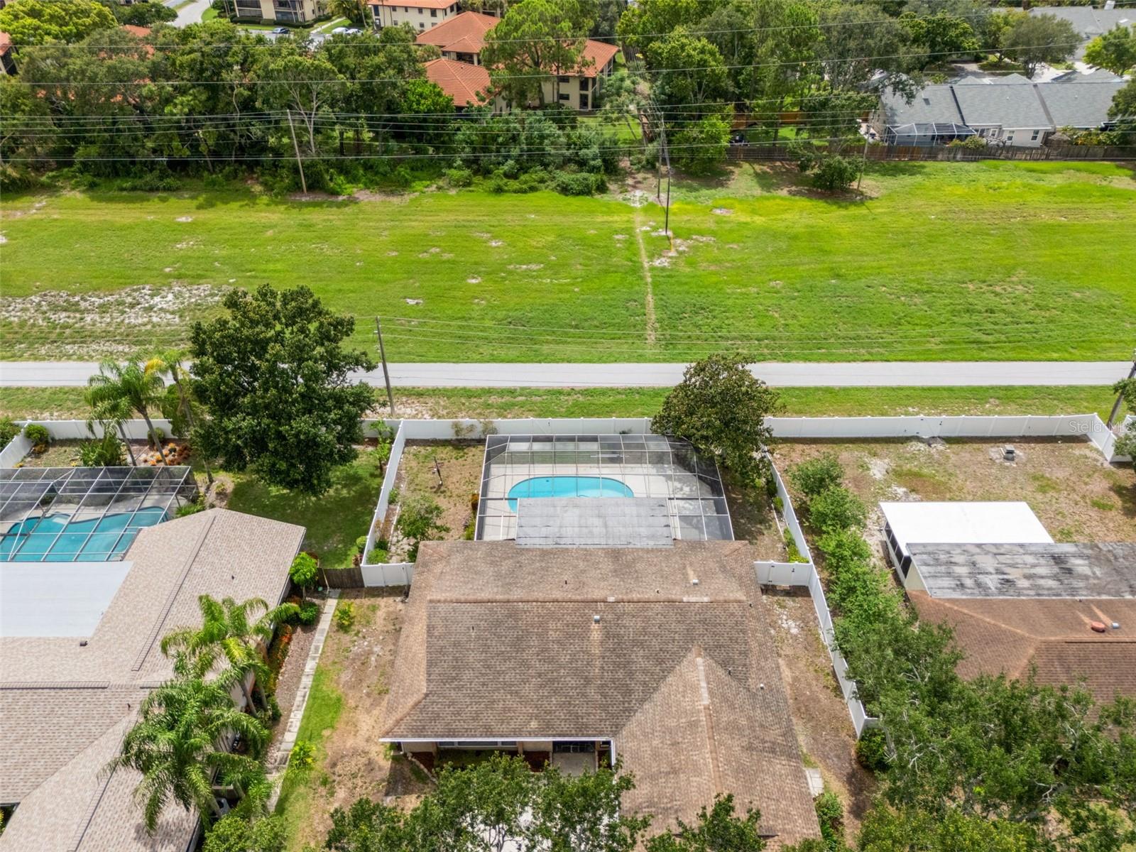 This vantage point places the pool and backyard within the context of the surrounding tree-lined neighborhood, underscoring the privacy of the fenced lot.