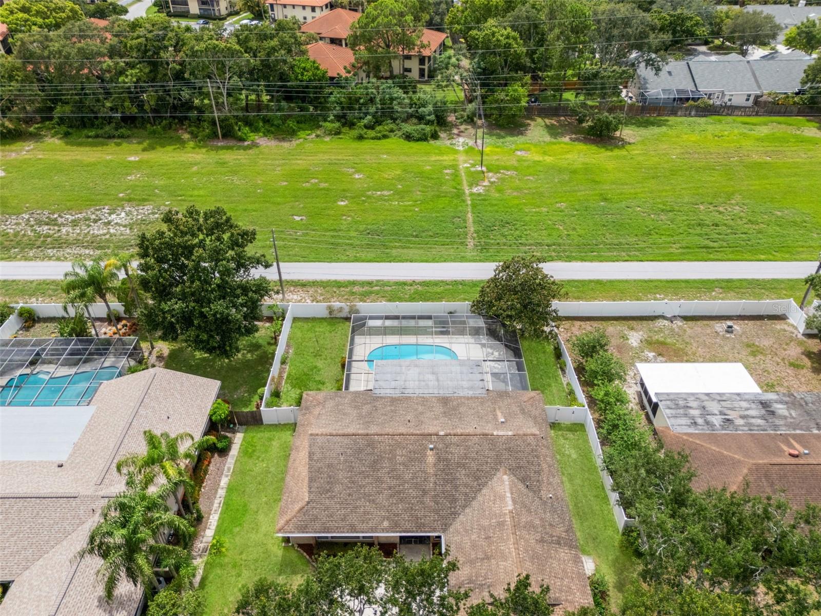 A wider aerial angle shows the home nestled among mature, oak-shaded landscaping within the established Clubhouse Estates and backing to the Duke Energy Trail.