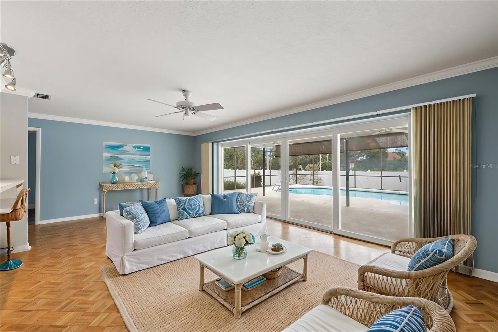 Warm parquet flooring and a pair of woven armchairs bring texture to this separate living space, tucked near the primary suite for a quieter retreat. Soft blue walls add a calming backdrop.