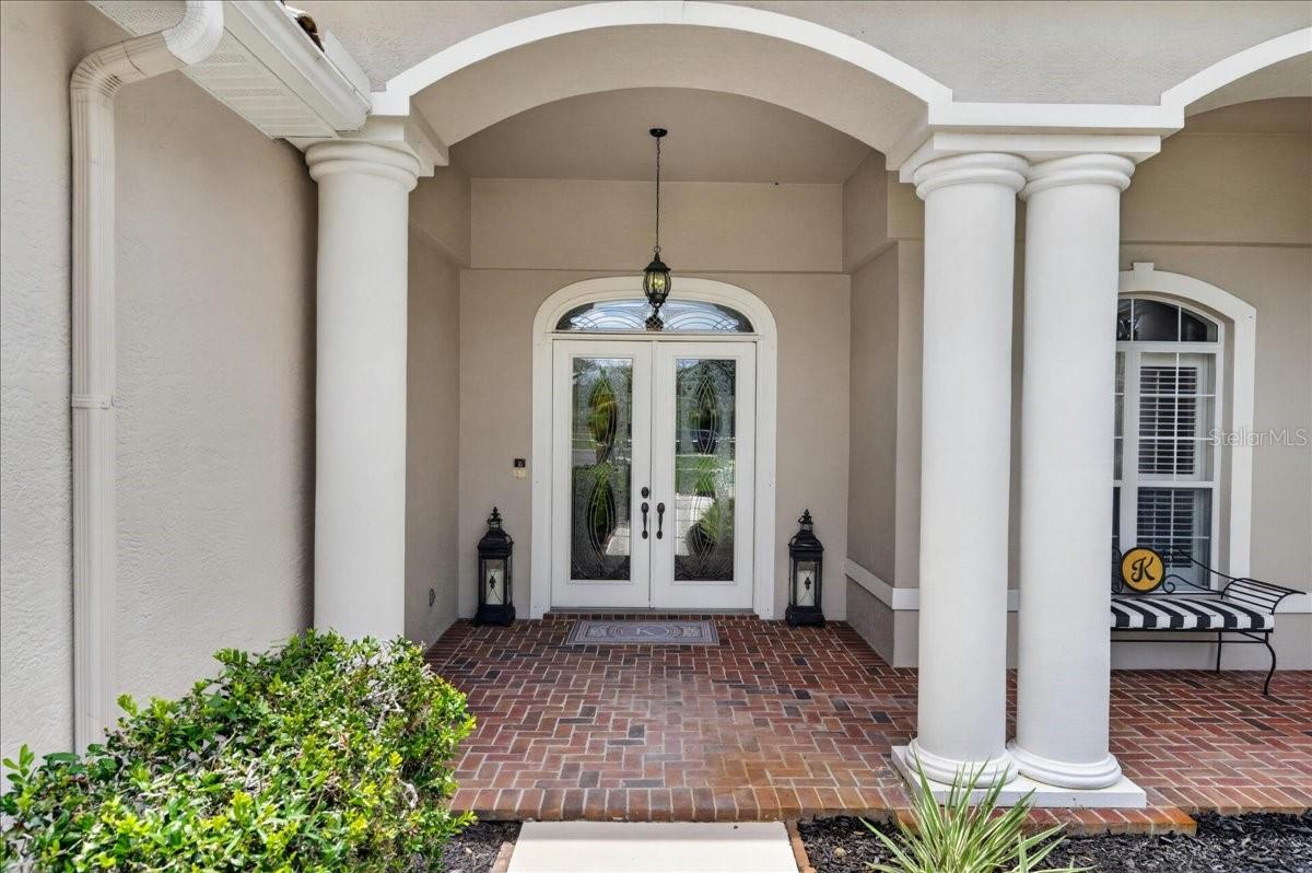 A stately covered entry with columns and leaded-glass double doors opens to a home that feels immediately grand, bright and inviting.