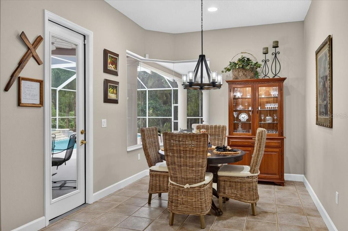 The adjoining breakfast nook is framed by a mitered-glass corner window overlooking the pool and preserve.