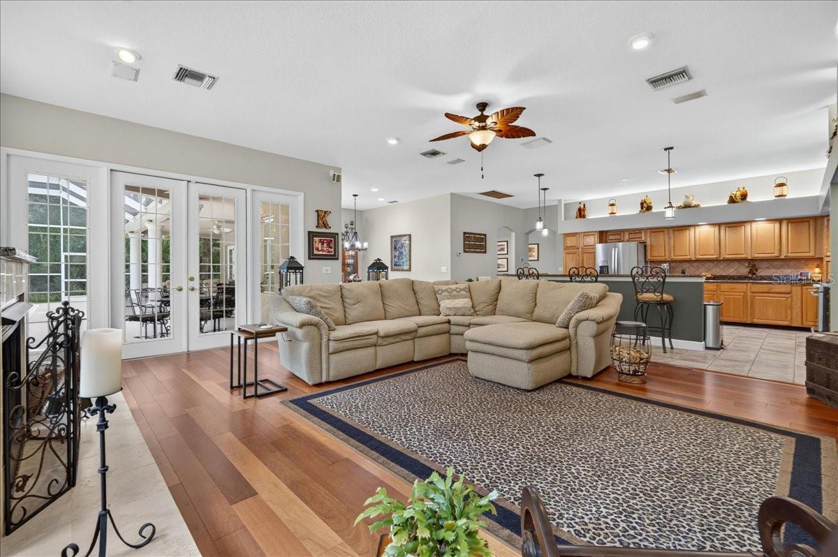 the impressive family room draws in the surrounding scenery through a striking arrangement of arched windows and multiple sets of French doors. Rich cherry wood floors and a gas fireplace bring warmth to this bright, open gathering space.