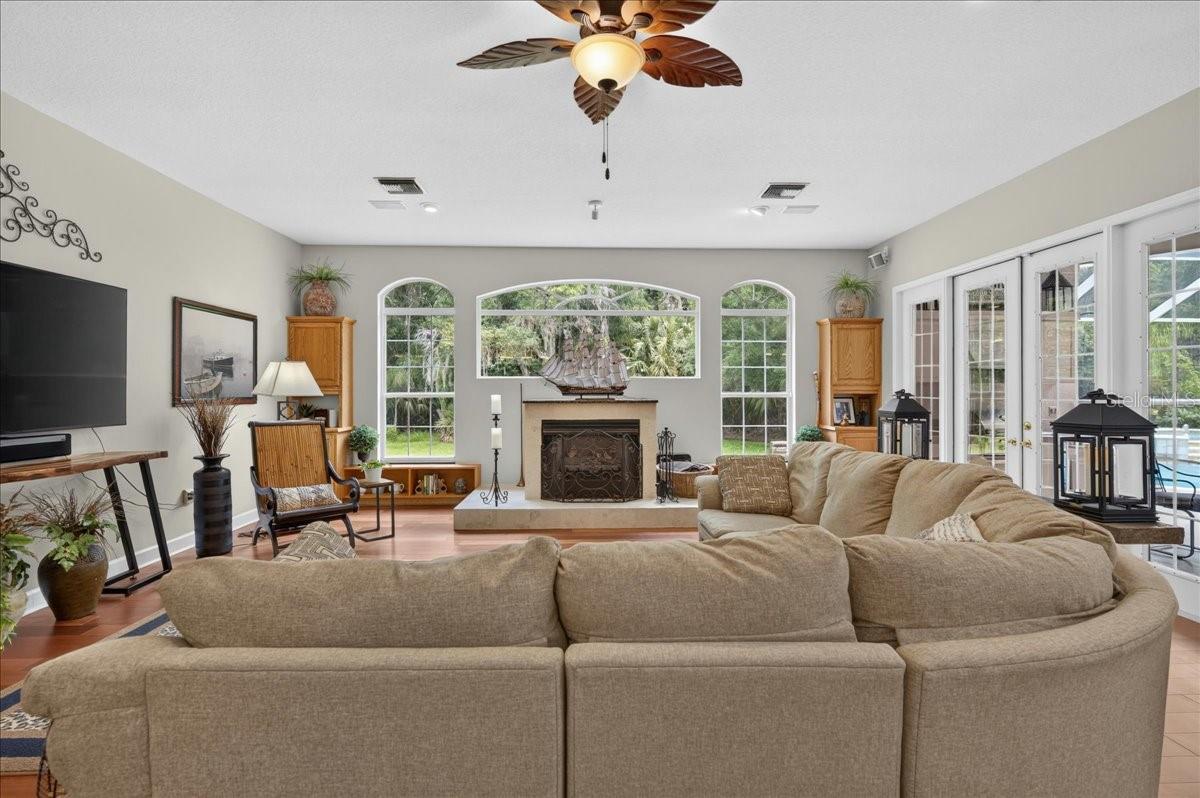 the impressive family room draws in the surrounding scenery through a striking arrangement of arched windows and multiple sets of French doors. Rich cherry wood floors and a gas fireplace bring warmth to this bright, open gathering space.
