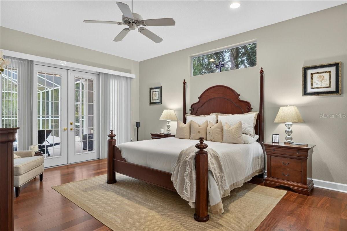 The primary bedroom retreat is set apart within the split-bedroom plan and features a transom window and French doors to the lanai and views beyond. Two walk-in closets with built-in organizers provide generous storage