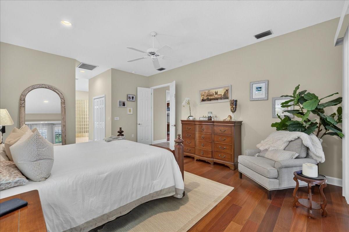 The primary bedroom retreat is set apart within the split-bedroom plan and features a transom window and French doors to the lanai and views beyond. Two walk-in closets with built-in organizers provide generous storage