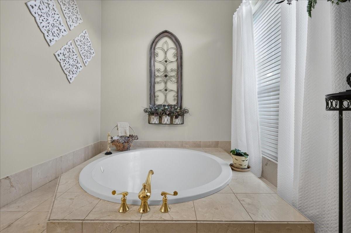 The ensuite bath offers extensive marble finishes, soaking tub, an oversized shower with a curved glass-block wall, double-sink vanity, and a separate water closet with bidet.
