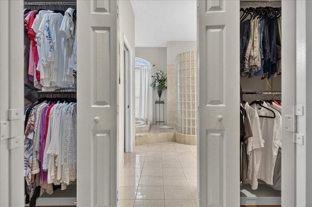 The primary bedroom retreat is set apart within the split-bedroom plan and features a transom window and French doors to the lanai and views beyond. Two walk-in closets with built-in organizers provide generous storage